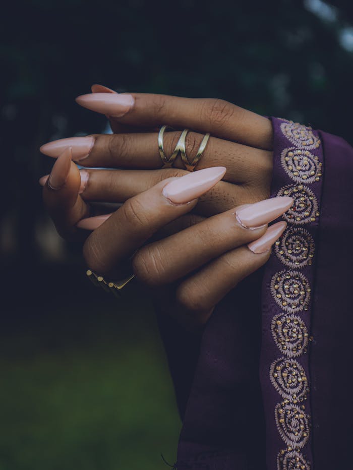 Close-up of hands wearing jewelry and embroidered fabric, showcasing cultural elegance.